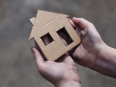 homeless boy holding a cardboard house