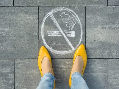 woman standing next to stop smoking signs