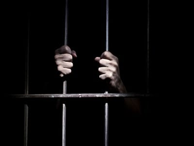 man in jail holding bars