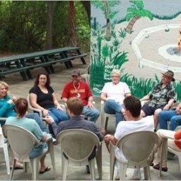 outdoor group therapy session with men and women sitting in front of campfire mural